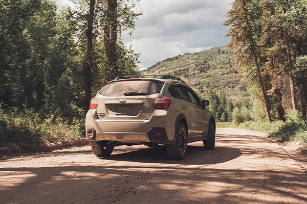 Tan Subaru Crosstrek on dirt road in mountains